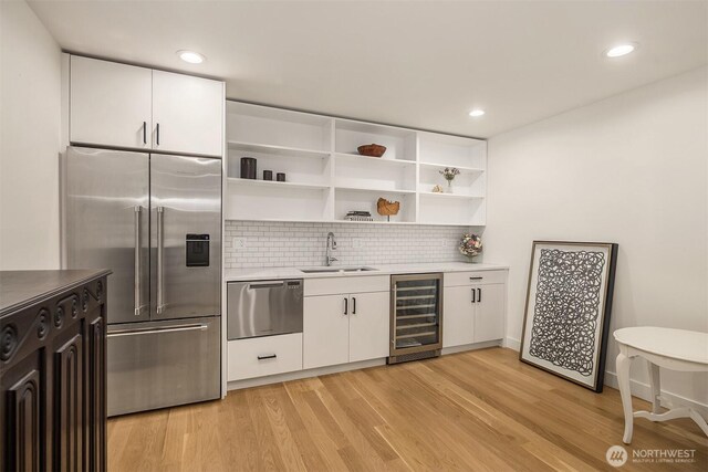 2809 NW 71st St, Seattle, WA 98117 - kitchen with beverage cooler, appliances with stainless steel finishes, white cabinets, backsplash, and recessed lighting