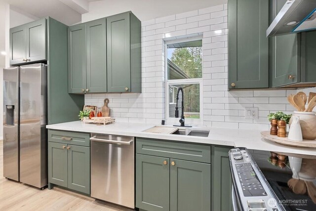 4968 Morgan Dr, Blaine, WA 98230 - kitchen with stainless steel appliances, green cabinets, under cabinet range hood, light countertops, and backsplash