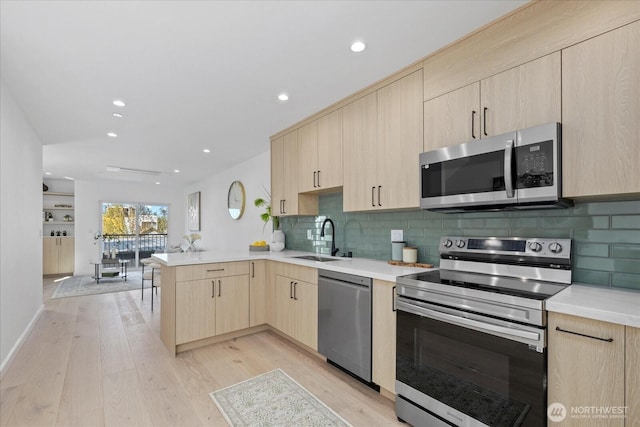 6032 42nd Ave SW Unit A, Seattle, WA 98136 - kitchen featuring appliances with stainless steel finishes, light brown cabinets, a peninsula, light wood finished floors, and recessed lighting