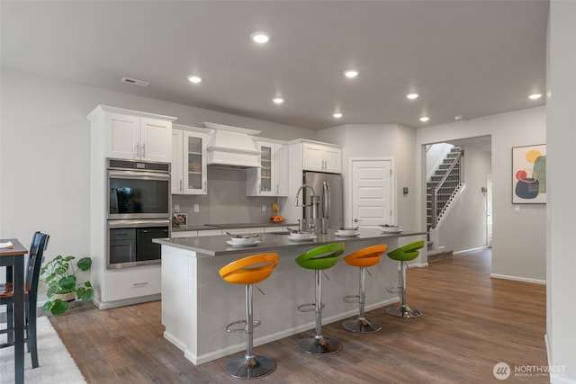 21124 42nd Dr SE, Bothell, WA 98021 - kitchen with stainless steel appliances, an island with sink, a breakfast bar, backsplash, and white cabinetry