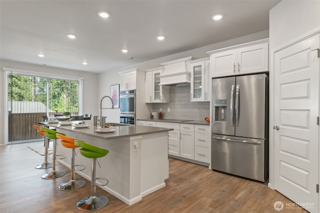 21124 42nd Dr SE, Bothell, WA 98021 - kitchen with stainless steel appliances, custom exhaust hood, a center island with sink, white cabinets, and wood finished floors