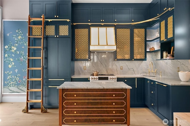 159 Denny Way Unit 112, Seattle, WA 98109 - kitchen with custom exhaust hood, electric range, light wood-style flooring, backsplash, and blue cabinetry