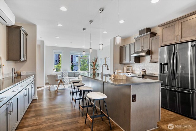 935 7th Ave NE Unit 17.3, Issaquah, WA 98029 - kitchen with stainless steel fridge with ice dispenser, under cabinet range hood, a wall mounted air conditioner, dark wood-type flooring, and a breakfast bar