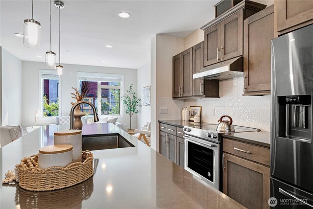 935 7th Ave NE Unit 17.3, Issaquah, WA 98029 - kitchen featuring stainless steel appliances, under cabinet range hood, decorative backsplash, dark countertops, and open floor plan