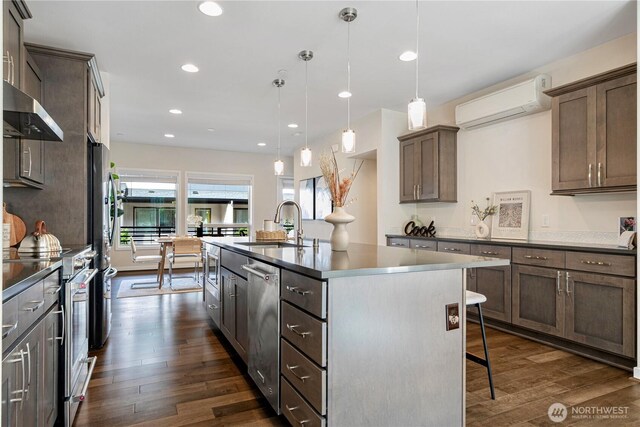 935 7th Ave NE Unit 17.3, Issaquah, WA 98029 - kitchen with appliances with stainless steel finishes, a wall mounted air conditioner, dark wood-style flooring, a kitchen island with sink, and a kitchen bar