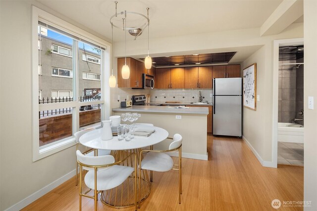 905 Cherry St Unit 101, Seattle, WA 98104 - kitchen featuring stainless steel appliances, light wood finished floors, tasteful backsplash, light countertops, and a peninsula