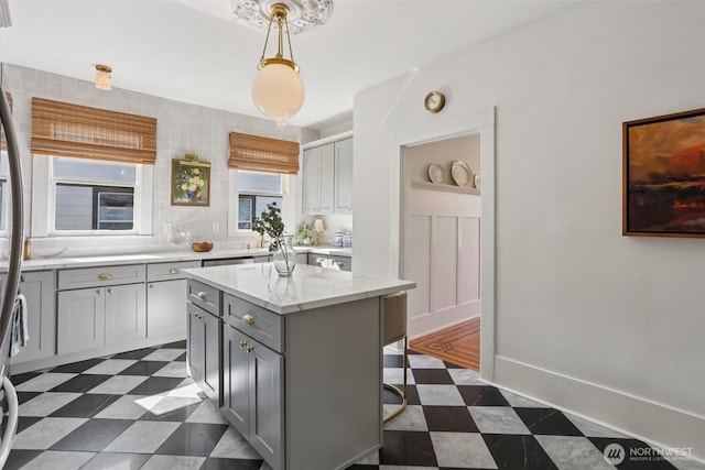 2233 2nd Ave W, Seattle, WA 98119 - kitchen with gray cabinetry, dark flooring, a center island, decorative light fixtures, and a breakfast bar area