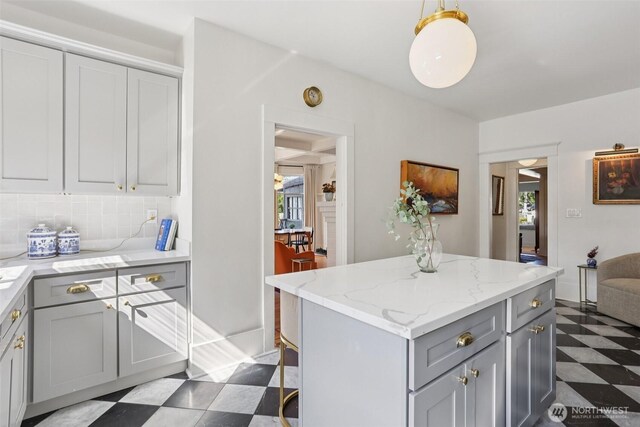 2233 2nd Ave W, Seattle, WA 98119 - kitchen featuring tile patterned floors, gray cabinetry, a center island, decorative backsplash, and light stone counters