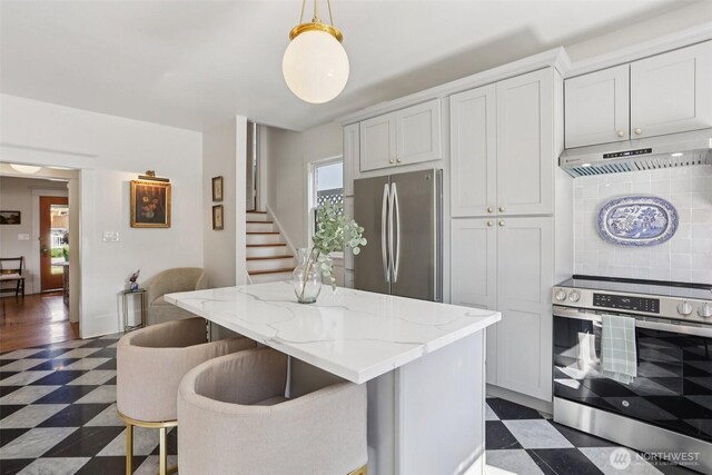 2233 2nd Ave W, Seattle, WA 98119 - kitchen with stainless steel appliances, dark flooring, under cabinet range hood, and a center island