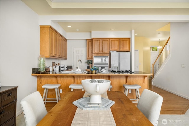 6290 Harbour Heights Parkway Unit A3, Mukilteo, WA 98275 - kitchen with white appliances, a breakfast bar area, light wood-style flooring, a peninsula, and brown cabinetry