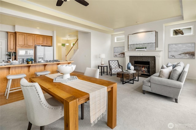 6290 Harbour Heights Parkway Unit A3, Mukilteo, WA 98275 - dining room featuring stairway, a tiled fireplace, crown molding, ceiling fan, and light carpet