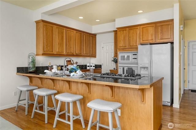 6290 Harbour Heights Parkway Unit A3, Mukilteo, WA 98275 - kitchen featuring white appliances, light wood-style floors, a peninsula, brown cabinets, and recessed lighting