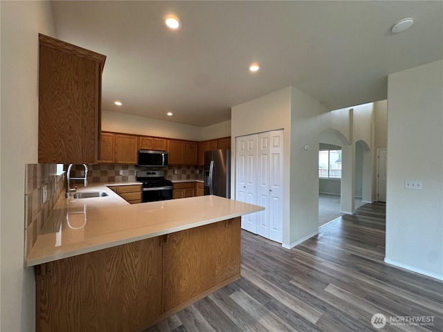 15328 104th Ave SE, Yelm, WA 98597 - kitchen featuring appliances with stainless steel finishes, arched walkways, wood finished floors, a peninsula, and light countertops