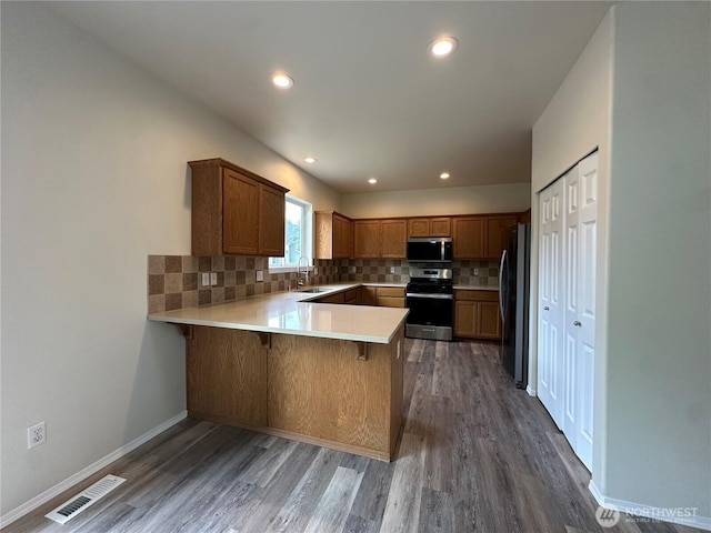 15328 104th Ave SE, Yelm, WA 98597 - kitchen featuring appliances with stainless steel finishes, a peninsula, wood finished floors, light countertops, and decorative backsplash