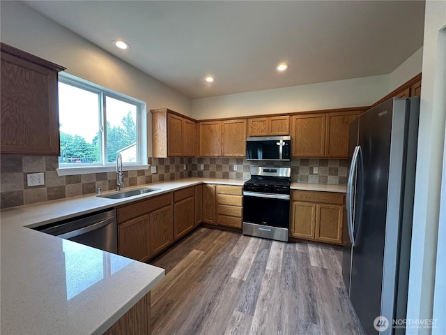 15328 104th Ave SE, Yelm, WA 98597 - kitchen with stainless steel appliances, wood finished floors, brown cabinetry, and recessed lighting