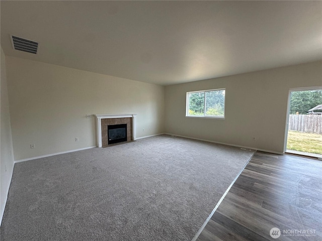 15328 104th Ave SE, Yelm, WA 98597 - unfurnished living room with plenty of natural light, a tiled fireplace, and wood finished floors