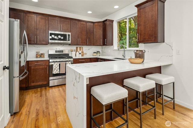16760 128th Pl NE, Woodinville, WA 98072 - kitchen featuring stainless steel appliances, a peninsula, light wood finished floors, recessed lighting, and light stone countertops