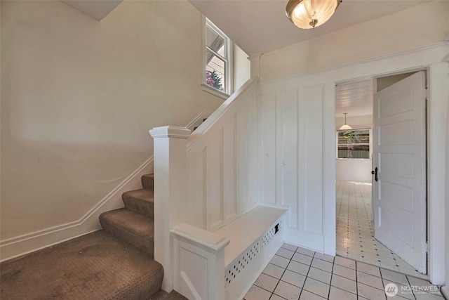715 W Howe St, Seattle, WA 98119 - staircase with a decorative wall, tile patterned flooring, and wainscoting