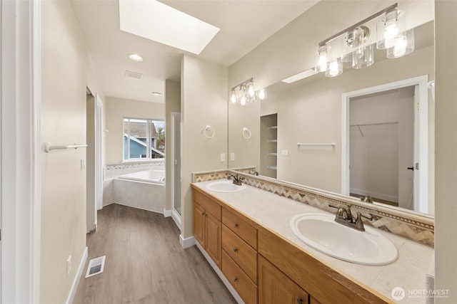 456 Sorensen St, Buckley, WA 98321 - full bath with wood finished floors, a bath, double vanity, a skylight, and a spacious closet