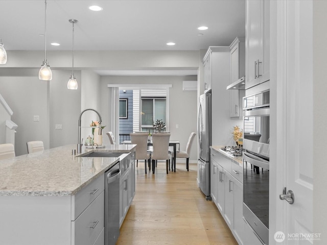 509 237th Pl SE Unit D, Bothell, WA 98021 - kitchen with appliances with stainless steel finishes, recessed lighting, an island with sink, light wood-style flooring, and light stone countertops