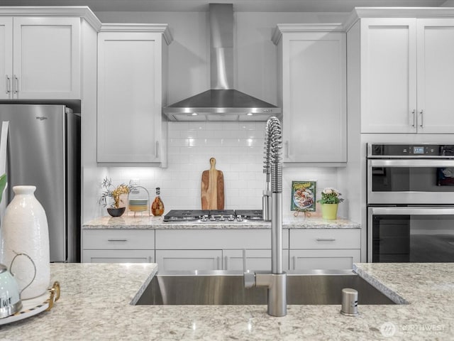 509 237th Pl SE Unit D, Bothell, WA 98021 - kitchen featuring wall chimney range hood, stainless steel appliances, decorative backsplash, and light stone counters