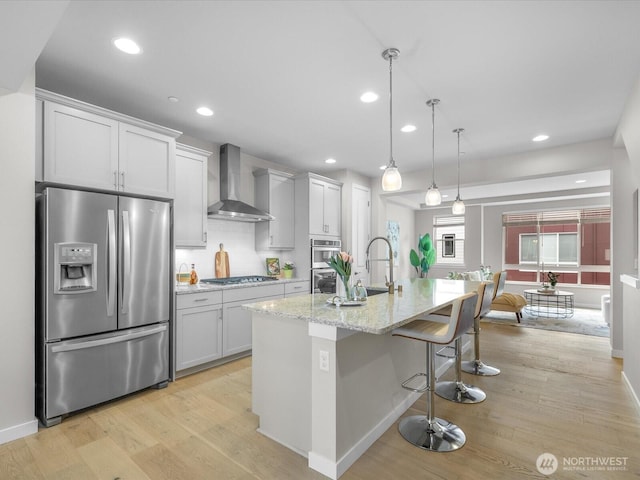 509 237th Pl SE Unit D, Bothell, WA 98021 - kitchen featuring stainless steel appliances, wall chimney exhaust hood, light wood-style floors, a kitchen breakfast bar, and recessed lighting