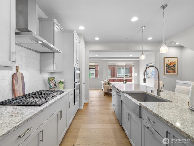 509 237th Pl SE Unit D, Bothell, WA 98021 - kitchen featuring wall chimney range hood, stainless steel appliances, recessed lighting, light wood finished floors, and tasteful backsplash