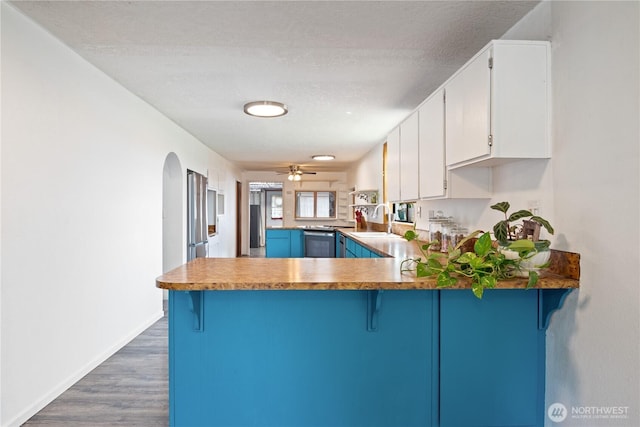 618 Main St, Vader, WA 98593 - kitchen featuring a peninsula, wood finished floors, white cabinets, a kitchen breakfast bar, and arched walkways
