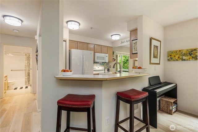 723 114th St SW Unit Y101, Everett, WA 98204 - kitchen featuring white appliances, light wood-style flooring, a breakfast bar area, and a peninsula