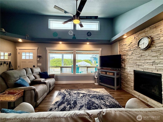 1155 Greenview Ave SW, Ocean Shores, WA 98569 - living area with a towering ceiling, ceiling fan, a stone fireplace, healthy amount of natural light, and wood finished floors