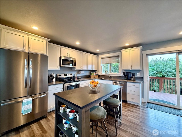 1155 Greenview Ave SW, Ocean Shores, WA 98569 - kitchen featuring stainless steel appliances, dark countertops, light wood finished floors, recessed lighting, and white cabinets