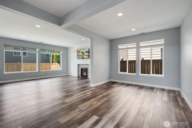 1130 77th Dr SE, Lake Stevens, WA 98258 - unfurnished living room with dark wood-type flooring, recessed lighting, a warm lit fireplace, and beamed ceiling