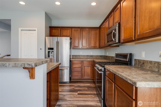 1130 77th Dr SE, Lake Stevens, WA 98258 - kitchen featuring stainless steel appliances, dark wood finished floors, a breakfast bar area, recessed lighting, and brown cabinets