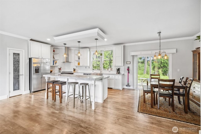1966 Hooker Rd, Sequim, WA 98382 - kitchen with stainless steel fridge, open shelves, wall chimney range hood, white cabinetry, and decorative backsplash