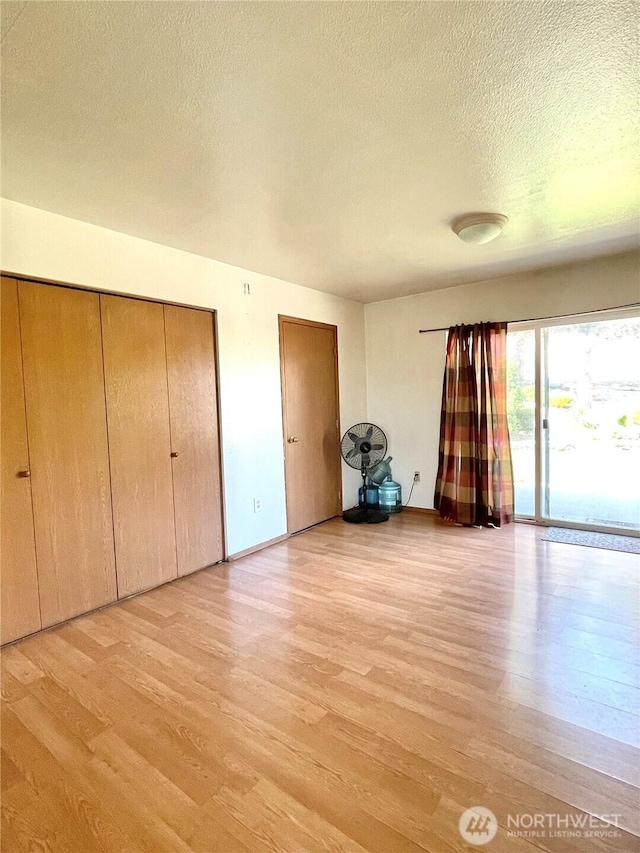 59G Copple Rd, Omak, WA 98841 - unfurnished bedroom with light wood-style flooring, a textured ceiling, access to outside, and two closets
