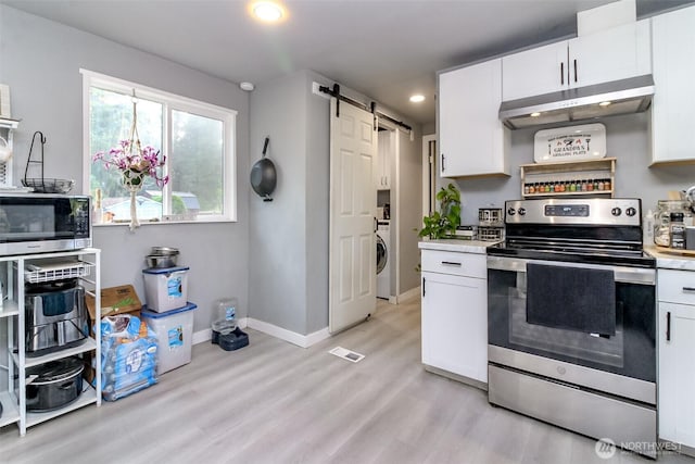 19820 63rd Avenue Ct E, Spanaway, WA 98387 - kitchen with stainless steel appliances, a barn door, under cabinet range hood, light countertops, and light wood-type flooring
