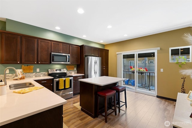 7162 Shinkle Pl SW Unit 64, Seattle, WA 98106 - kitchen with stainless steel appliances, light countertops, a breakfast bar area, dark brown cabinetry, and light wood-style flooring