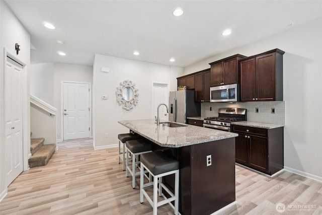7608 16th Pl SE, Lake Stevens, WA 98258 - kitchen featuring stainless steel appliances, a kitchen breakfast bar, light wood-type flooring, tasteful backsplash, and recessed lighting