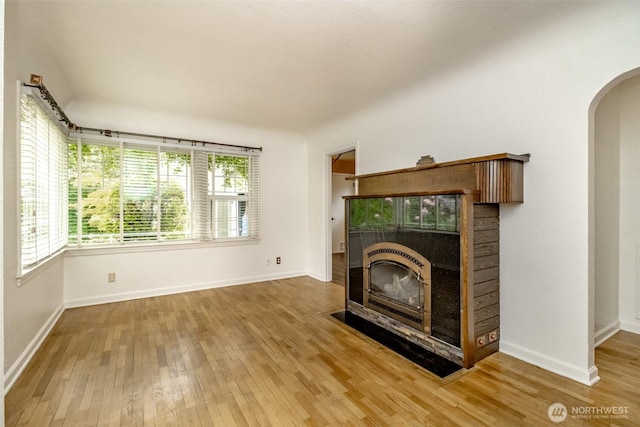 6711 100th St SW, Lakewood, WA 98499 - unfurnished living room featuring arched walkways, wood finished floors, and a fireplace