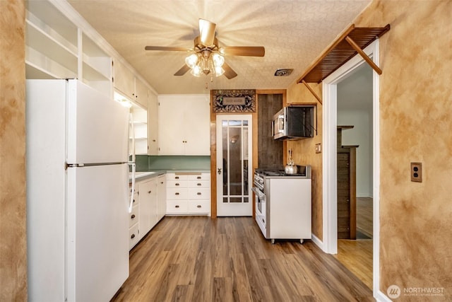 6711 100th St SW, Lakewood, WA 98499 - kitchen with white appliances, ceiling fan, wood finished floors, and white cabinets