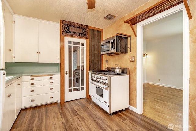 6711 100th St SW, Lakewood, WA 98499 - kitchen featuring range with gas stovetop, stainless steel microwave, light wood-type flooring, and white cabinetry