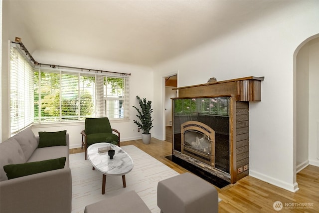 6711 100th St SW, Lakewood, WA 98499 - living room featuring arched walkways, light wood-type flooring, and a tile fireplace