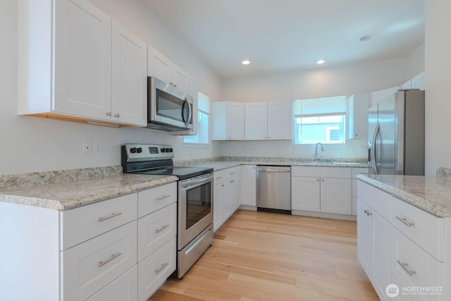 18768 1st Ave NE, Suquamish, WA 98392 - kitchen featuring stainless steel appliances, white cabinets, light wood-type flooring, recessed lighting, and light stone counters