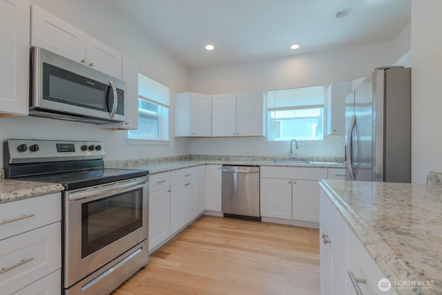 18768 1st Ave NE, Suquamish, WA 98392 - kitchen featuring stainless steel appliances, white cabinetry, light stone countertops, light wood-style flooring, and recessed lighting
