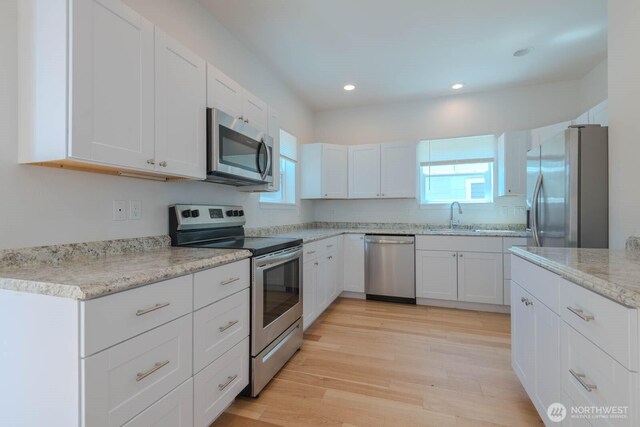 18768 1st Ave NE, Suquamish, WA 98392 - kitchen featuring appliances with stainless steel finishes, light wood-style flooring, white cabinets, recessed lighting, and light stone counters