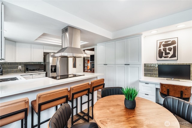830 S 301st Pl, Federal Way, WA 98003 - kitchen featuring island range hood, black electric cooktop, stainless steel fridge with ice dispenser, a breakfast bar area, and tasteful backsplash
