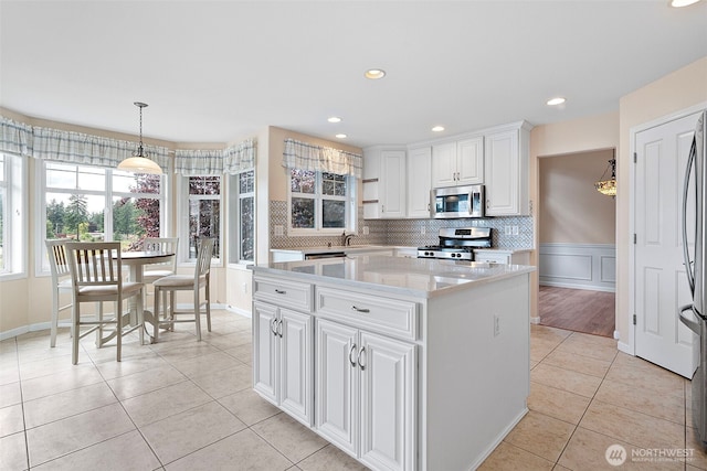 22019 84th Avenue Ct E, Graham, WA 98338 - kitchen with stainless steel appliances, light tile patterned floors, a kitchen island, white cabinetry, and decorative light fixtures