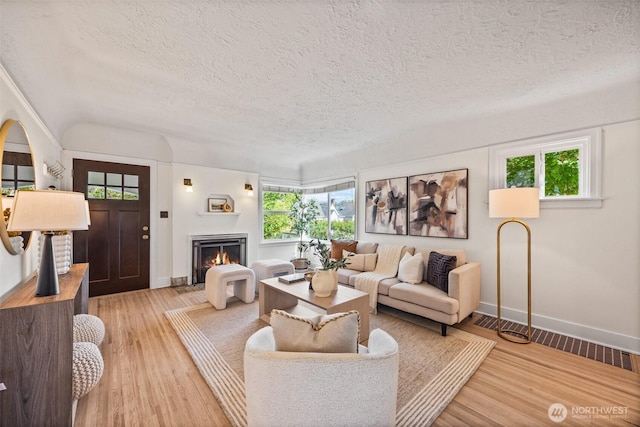 6543 12th Ave NW, Seattle, WA 98117 - living room featuring healthy amount of natural light, a textured ceiling, a warm lit fireplace, and light wood-style flooring