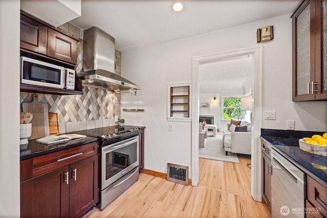 6543 12th Ave NW, Seattle, WA 98117 - kitchen featuring appliances with stainless steel finishes, wall chimney range hood, light wood-type flooring, and tasteful backsplash