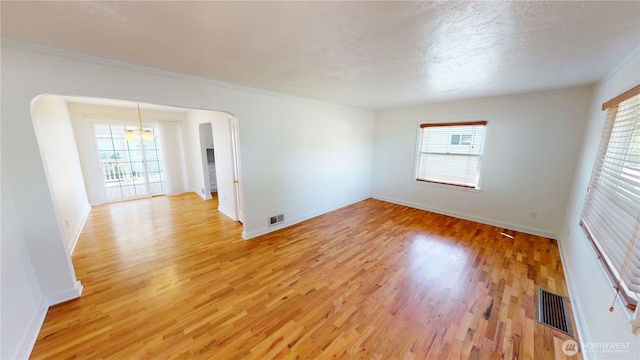 1303 Modoc, Walla Walla, WA 99362 - unfurnished room featuring plenty of natural light, light wood-style flooring, ornamental molding, and arched walkways